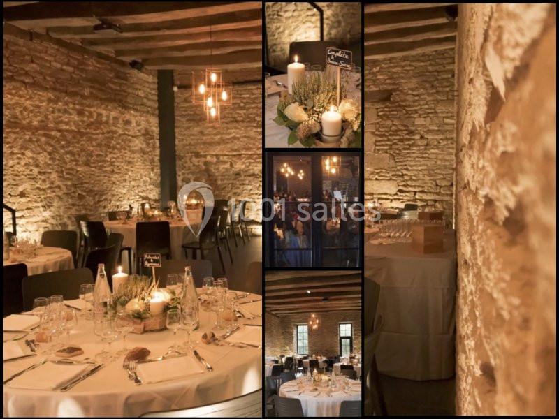 Salle de réception en pierre apparente avec tables décorées de bougies et fleurs, ambiance chaleureuse et éclairage tamisé.
