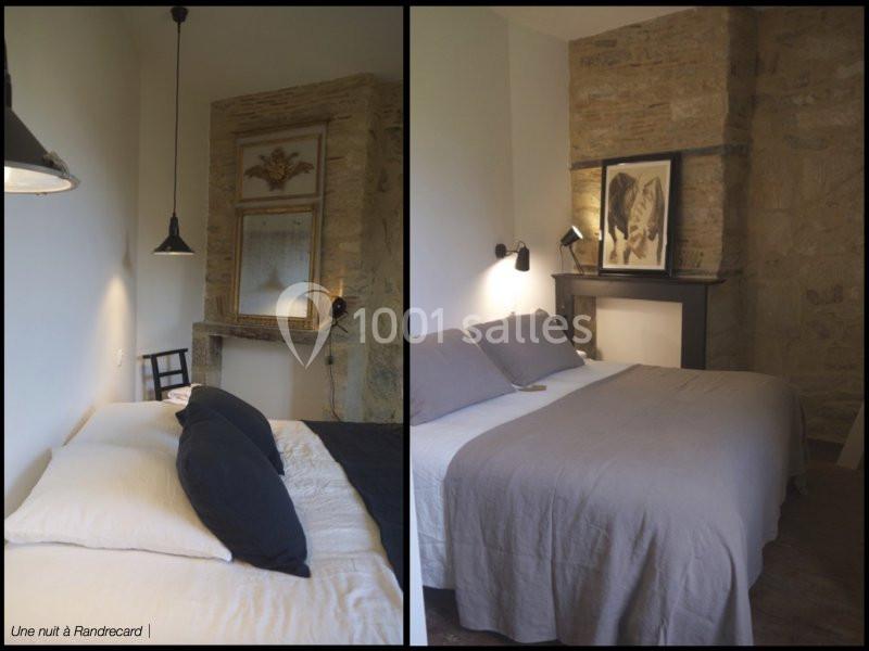 Chambre avec lit double, murs en pierre apparente, éclairage doux et décoration sobre.