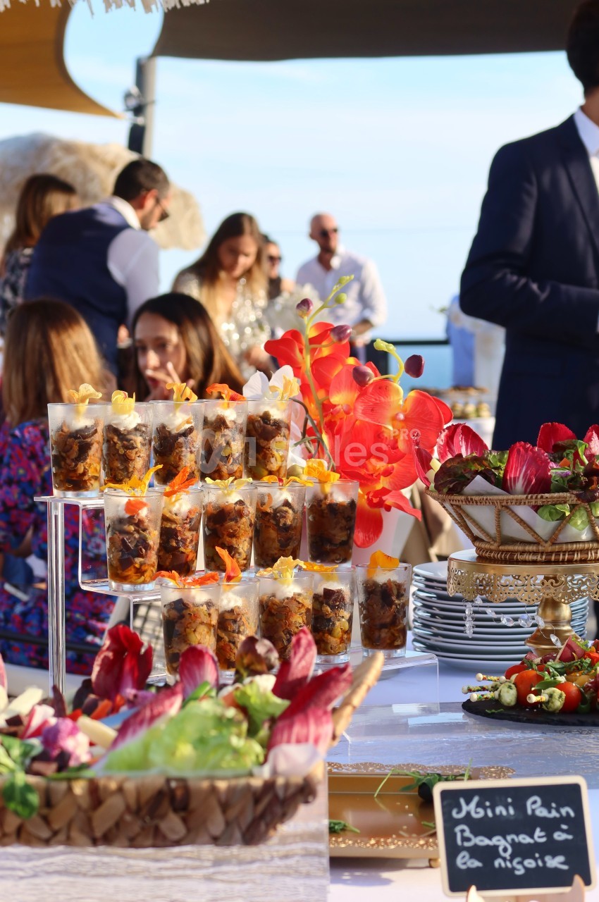 Buffet en plein air avec verrines, fleurs décoratives et assiettes garnies de légumes colorés.