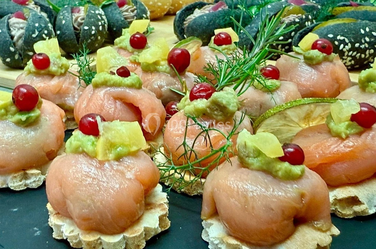 Assortiment de bouchées au saumon fumé, garnies d'avocat, ananas, canneberges et herbes fraîches sur des toasts.