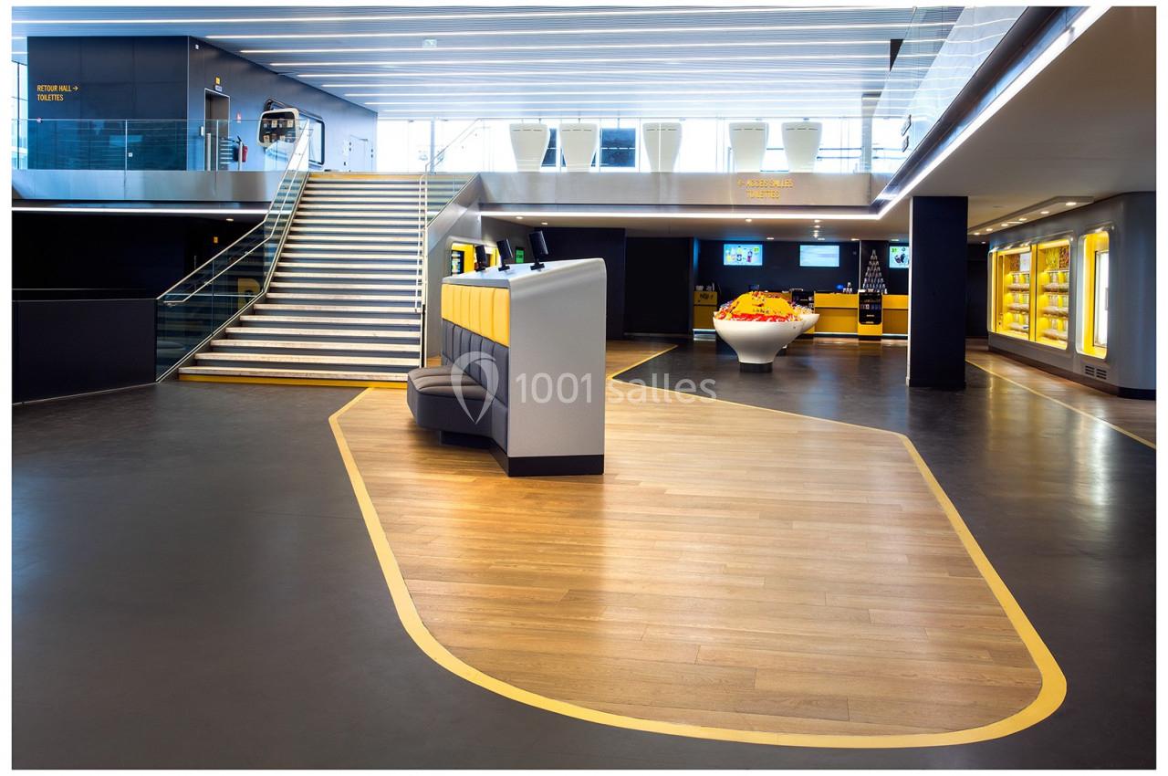 Espace intérieur moderne avec escalier, mobilier design et éclairage lumineux, sol en bois et zones délimitées.