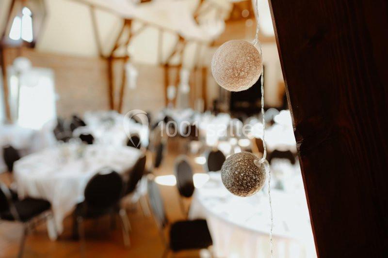 Location salle Watten (Nord) - Le Domaine du Fil de l’Eau #4 Décoration lumineuse suspendue avec des boules en fil tressé, en arrière-plan une salle de réception avec tables dressées.