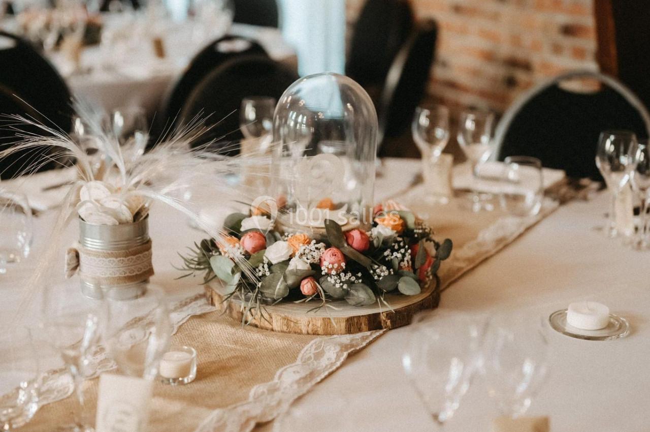 Location salle Watten (Nord) - Le Domaine du Fil de l’Eau #17 Table décorée pour un événement avec centre de table floral sous cloche en verre, nappes beige et vaisselle élégante.