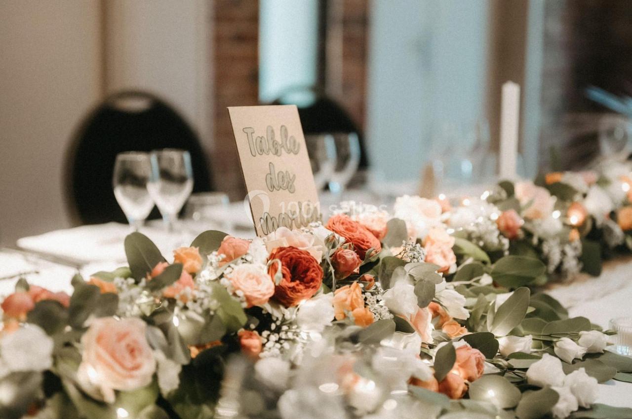 Location salle Watten (Nord) - Le Domaine du Fil de l’Eau #16 Décoration de table avec un centre de table floral composé de roses et feuillage, dans une salle aux murs en briques.