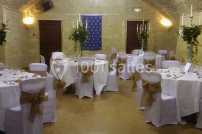 Château en pierre éclairé par des lampadaires au crépuscule, entouré d'arbres et d'une allée gravillonnée.