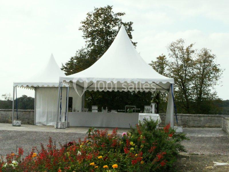 Deux tentes blanches montées sur une terrasse, avec un comptoir et des fleurs au premier plan.