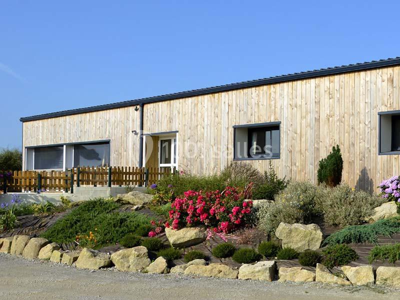 Bâtiment en bois avec des fenêtres modernes, entouré d'un jardin fleuri et de rochers décoratifs.