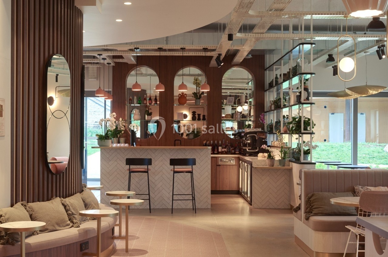Espace intérieur moderne avec bar central, mobilier en bois, miroirs arrondis et lumière naturelle entrant par une baie…