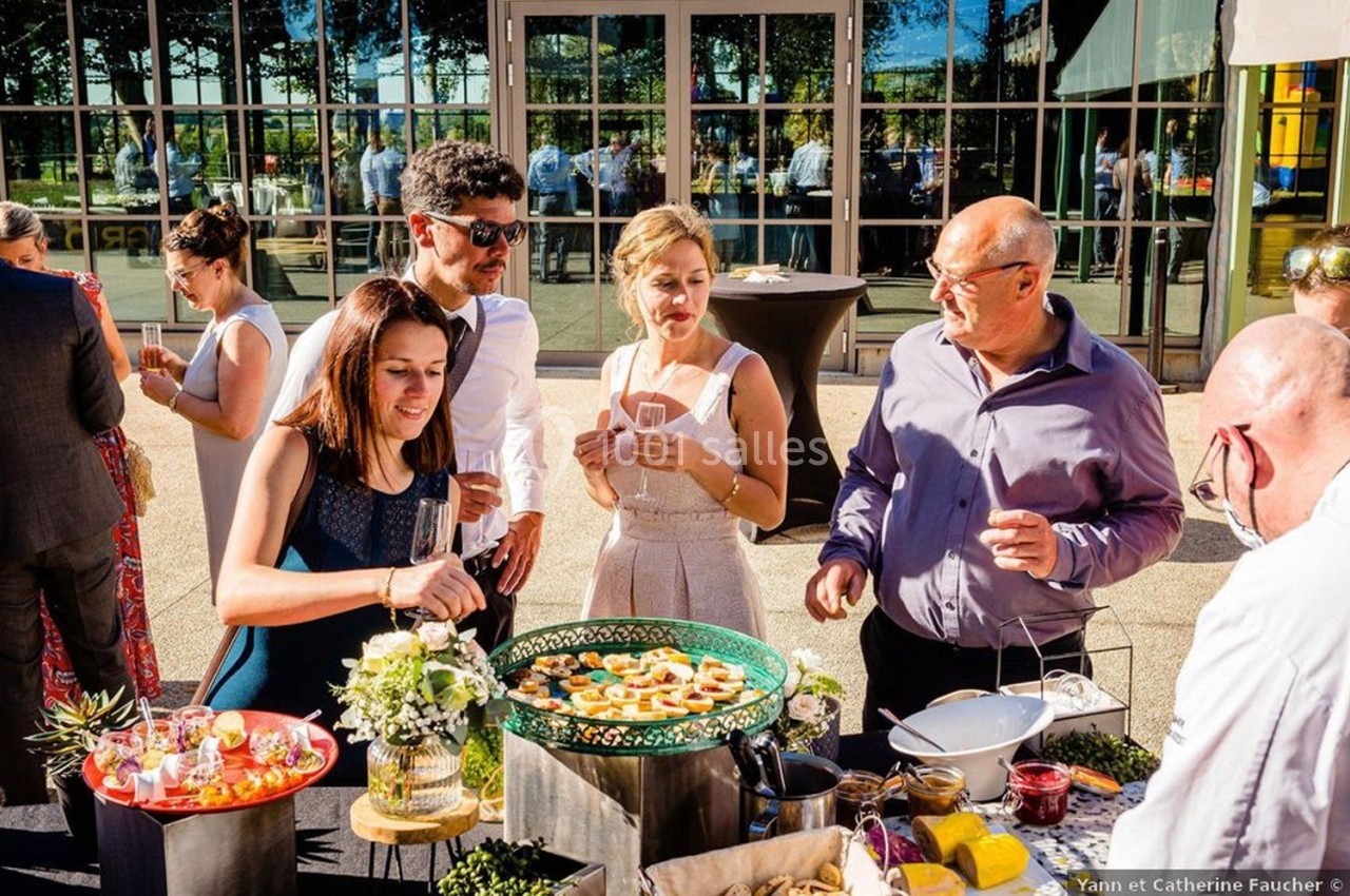Des personnes se servant et discutant autour d'un buffet en extérieur lors d'un événement en journée.