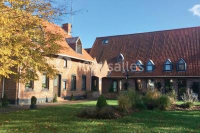 Tente blanche installée sur une pelouse, accueillant un événement avec des invités debout autour de tables hautes.