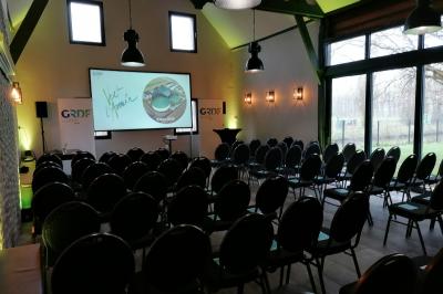 Tente blanche installée sur une pelouse, accueillant un événement avec des invités debout autour de tables hautes.