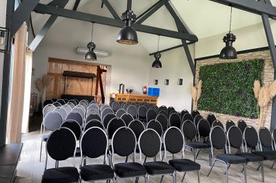 Tente blanche installée sur une pelouse, accueillant un événement avec des invités debout autour de tables hautes.