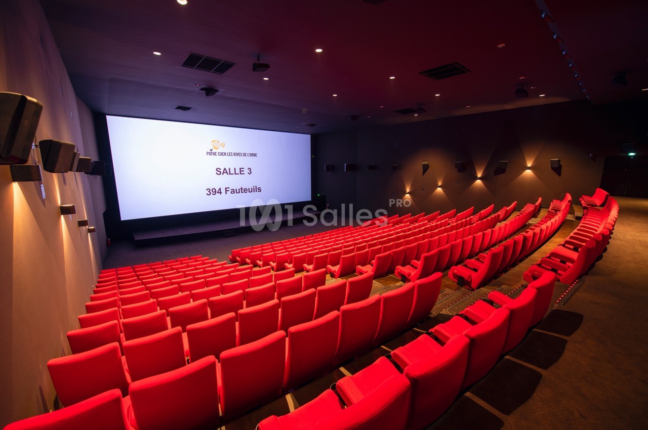 Salle de cinéma vide avec des rangées de fauteuils rouges et un écran affichant ’Salle 3, 394 fauteuils’.