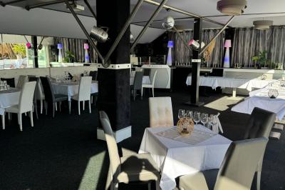 Miniature Location salle Marseille (Bouches-du-Rhône) - Le Greenwich #7 Salle de restaurant lumineuse avec tables dressées, chaises noires et blanches, et terrasse extérieure avec vue sur des…