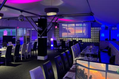 Miniature Location salle Marseille (Bouches-du-Rhône) - Le Greenwich #5 Salle de restaurant lumineuse avec tables dressées, chaises noires et blanches, et terrasse extérieure avec vue sur des…