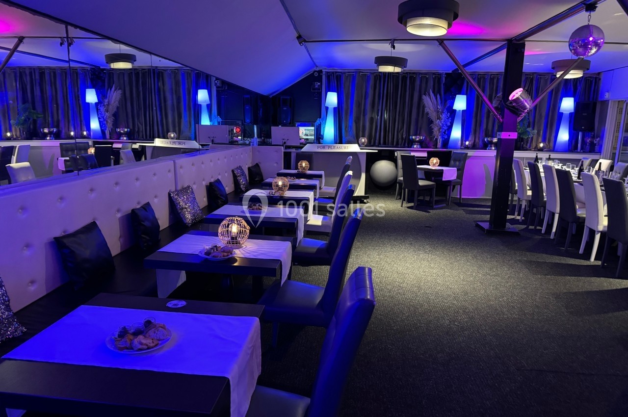 Salle de restaurant moderne avec tables dressées, éclairage tamisé et ambiance lumineuse bleutée.