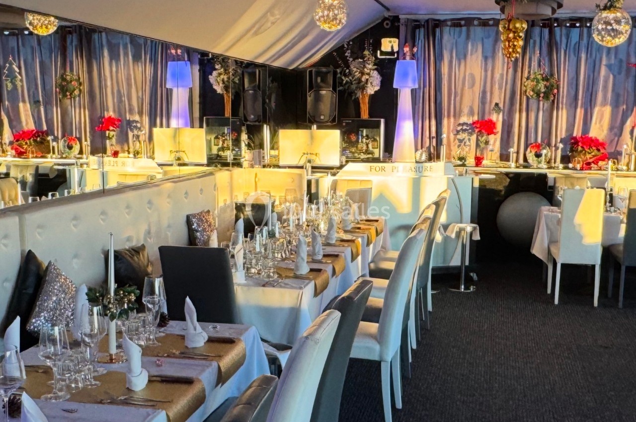 Salle de réception élégante avec tables dressées, décorations festives, et éclairage chaleureux.