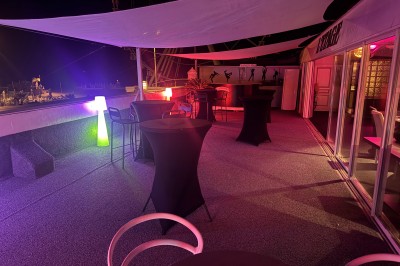 Miniature Location salle Marseille (Bouches-du-Rhône) - Le Greenwich #26 Terrasse extérieure éclairée de nuit avec tables hautes, chaises et décorations lumineuses sous des voiles tendues.