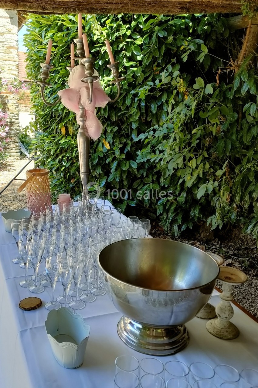 Table dressée en extérieur avec des verres à pied, un grand seau à champagne, un chandelier et des décorations.