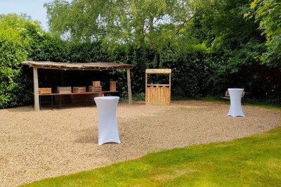 Voiture ancienne blanche décorée de fleurs, stationnée devant un bâtiment en pierre avec un toit en ardoise.
