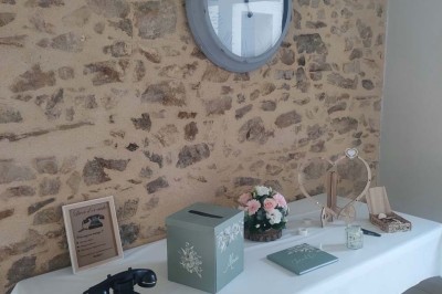 Voiture ancienne blanche décorée de fleurs, stationnée devant un bâtiment en pierre avec un toit en ardoise.