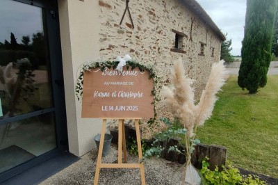 Voiture ancienne blanche décorée de fleurs, stationnée devant un bâtiment en pierre avec un toit en ardoise.