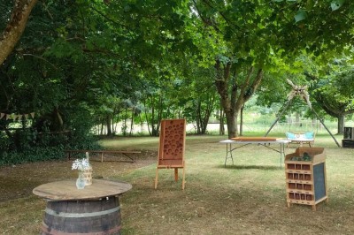 Voiture ancienne blanche décorée de fleurs, stationnée devant un bâtiment en pierre avec un toit en ardoise.