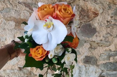 Voiture ancienne blanche décorée de fleurs, stationnée devant un bâtiment en pierre avec un toit en ardoise.