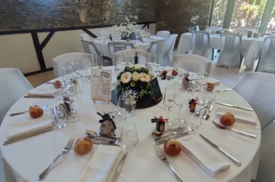 Voiture ancienne blanche décorée de fleurs, stationnée devant un bâtiment en pierre avec un toit en ardoise.