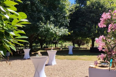 Voiture ancienne blanche décorée de fleurs, stationnée devant un bâtiment en pierre avec un toit en ardoise.