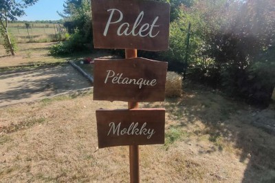 Voiture ancienne blanche décorée de fleurs, stationnée devant un bâtiment en pierre avec un toit en ardoise.