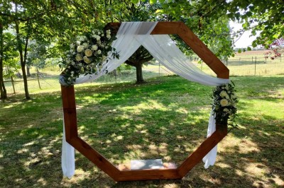 Voiture ancienne blanche décorée de fleurs, stationnée devant un bâtiment en pierre avec un toit en ardoise.