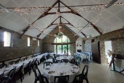 Voiture ancienne blanche décorée de fleurs, stationnée devant un bâtiment en pierre avec un toit en ardoise.