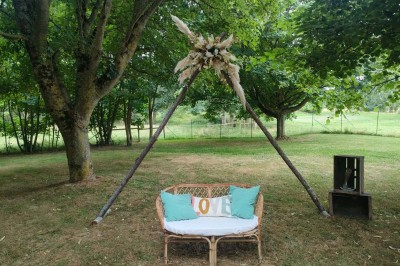 Voiture ancienne blanche décorée de fleurs, stationnée devant un bâtiment en pierre avec un toit en ardoise.