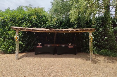 Voiture ancienne blanche décorée de fleurs, stationnée devant un bâtiment en pierre avec un toit en ardoise.