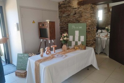 Voiture ancienne blanche décorée de fleurs, stationnée devant un bâtiment en pierre avec un toit en ardoise.