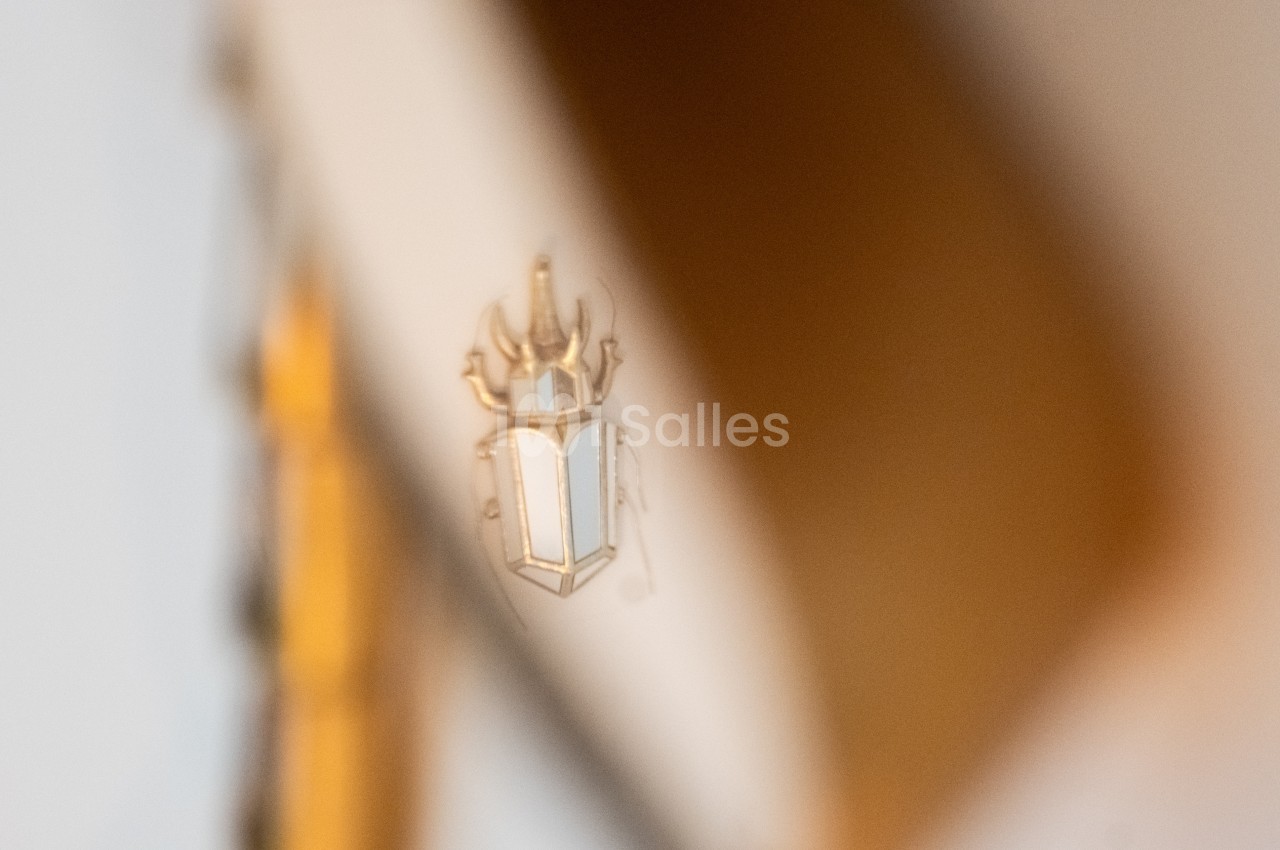 Reflet flou d'un blason doré et blanc sur une surface brillante, avec un arrière-plan beige.