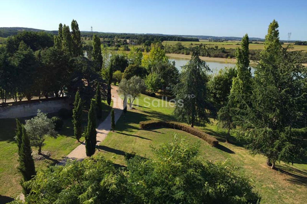 Vue d'un parc arboré avec des allées sinueuses, bordé par une rivière et entouré de paysages ruraux.