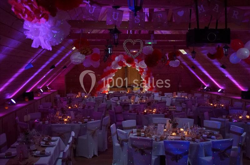 Salle de réception décorée pour un mariage avec tables dressées, guirlandes lumineuses et ballons colorés.