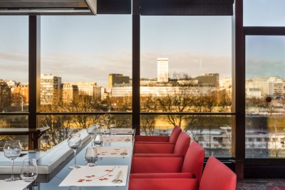 Miniature Benkay Vue de Paris à travers une fenêtre, montrant la Seine, un bâtiment moderne et l'horizon urbain avec des gratte-ciels.
