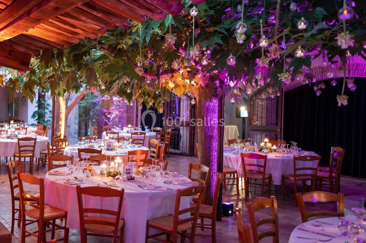 Location salle Gémenos (Bouches-du-Rhône) - Moulin de Gemenos #3 Salle de réception décorée avec des tables rondes dressées, éclairage tamisé et végétation suspendue.