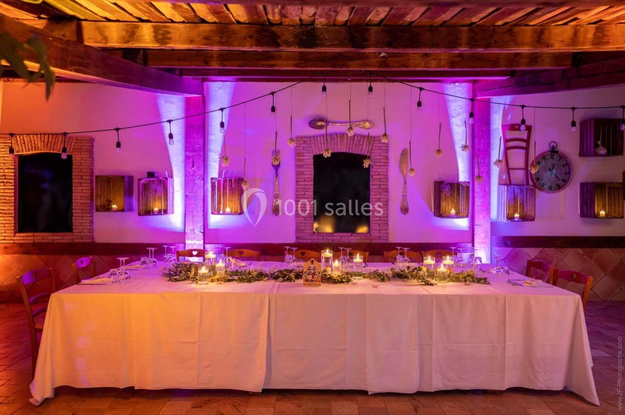 Location salle Gémenos (Bouches-du-Rhône) - Moulin de Gemenos #5 Table décorée pour un dîner, éclairée par des guirlandes lumineuses et des bougies, dans une salle aux murs en pierre.