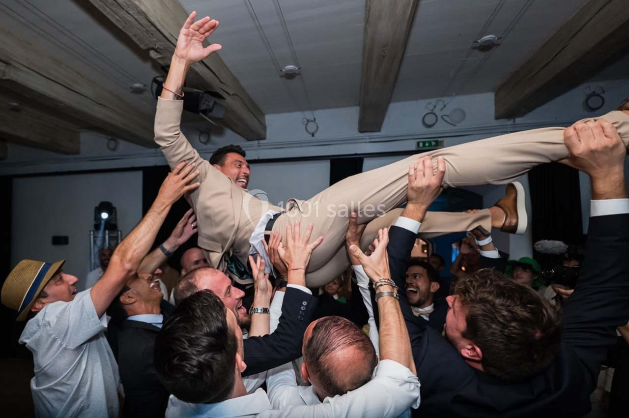 Location salle Gémenos (Bouches-du-Rhône) - Moulin de Gemenos #9 Un groupe d'hommes soulève un homme en costume beige lors d'une célébration dans une salle.