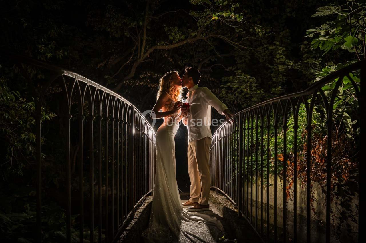 Location salle Gémenos (Bouches-du-Rhône) - Moulin de Gemenos #18 Un couple élégant se tient sur un pont éclairé la nuit, partageant un moment romantique.