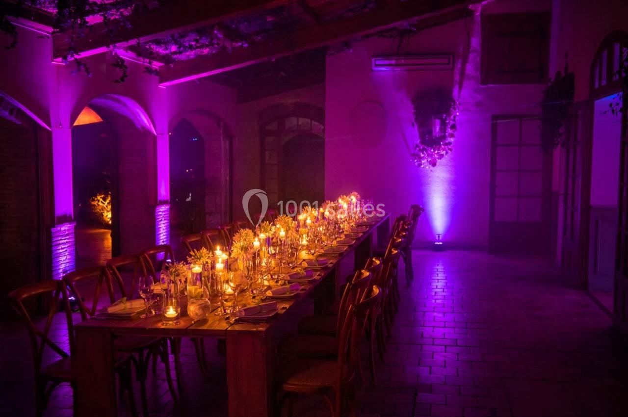 Location salle Gémenos (Bouches-du-Rhône) - Moulin de Gemenos #41 Table décorée avec des bougies et des verres dans une salle tamisée éclairée par des lumières violettes.
