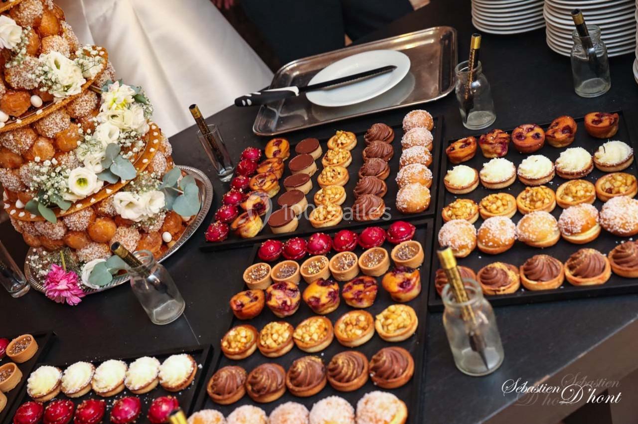 Location salle Gémenos (Bouches-du-Rhône) - Moulin de Gemenos #52 Plateau de desserts variés avec un croquembouche décoré de fleurs en arrière-plan sur une table de réception.