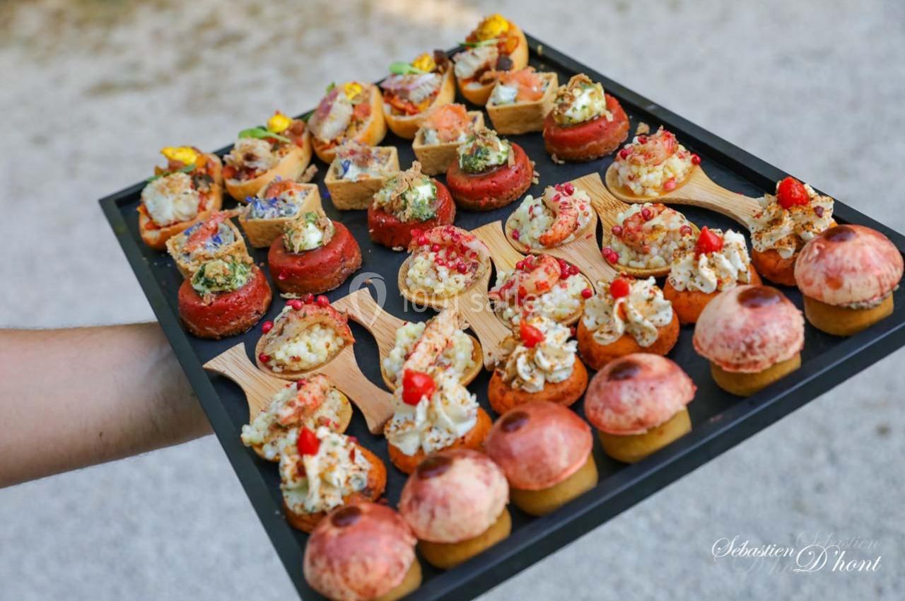 Location salle Gémenos (Bouches-du-Rhône) - Moulin de Gemenos #56 Plateau de bouchées apéritives variées présentées sur un support noir, tenu par une main.