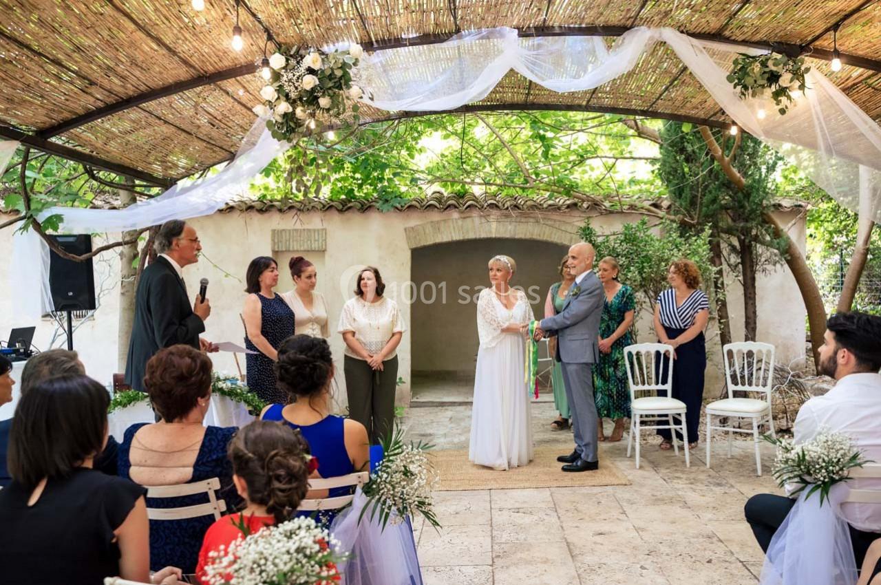 Location salle Gémenos (Bouches-du-Rhône) - Moulin de Gemenos #64 Un couple échange ses vœux lors d'une cérémonie de mariage en extérieur sous une pergola décorée.