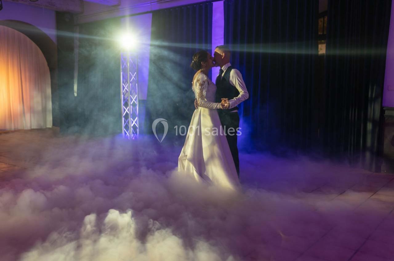 Location salle Gémenos (Bouches-du-Rhône) - Moulin de Gemenos #70 Un couple de mariés danse dans une ambiance éclairée par des projecteurs et entourée de fumée au sol.