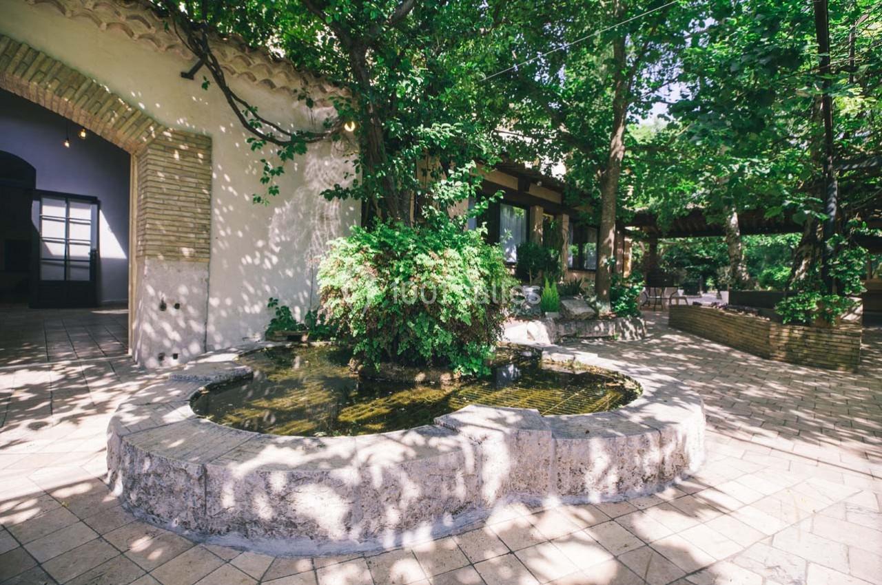 Location salle Gémenos (Bouches-du-Rhône) - Moulin de Gemenos #83 Cour intérieure ombragée avec une fontaine centrale entourée de végétation et de pavés clairs.